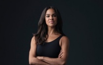 Misty Copeland with arms crossed in front of a dark background. 