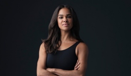 Misty Copeland with arms crossed in front of a dark background. 