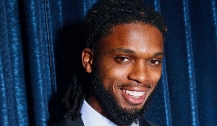 damar hamlin smiling in front of a velvet curtain. 