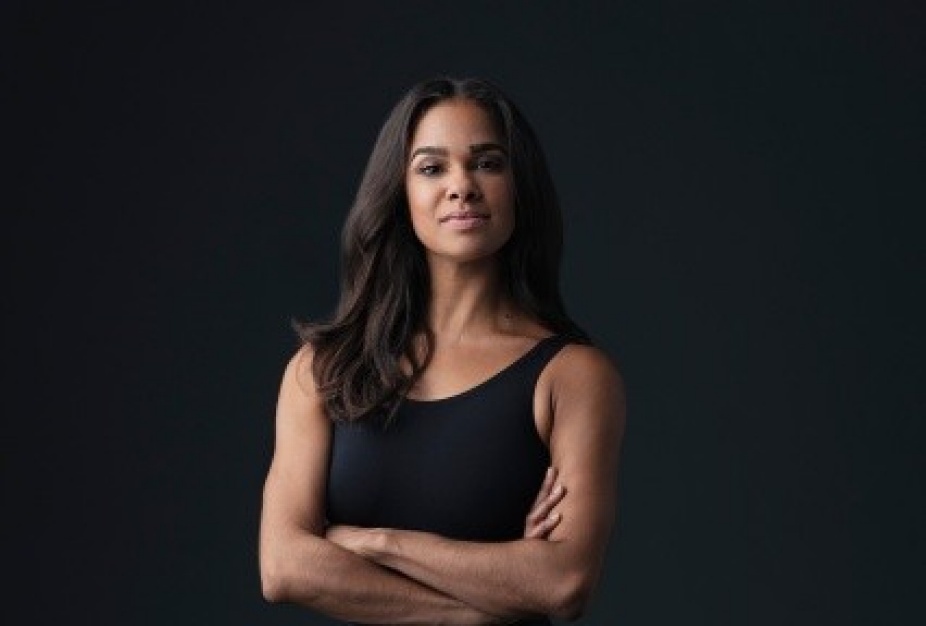 misty copeland in front of dark background with arms crossed. 