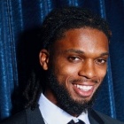 damar hamlin in front of a velvet curtain wearing a suit. 