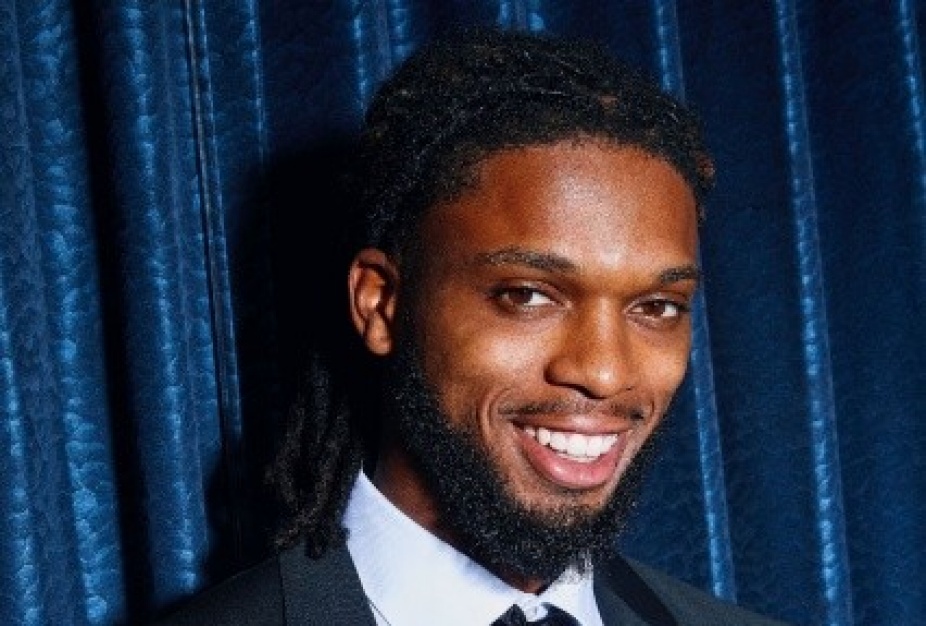 damar hamlin in front of a velvet curtain wearing a suit. 