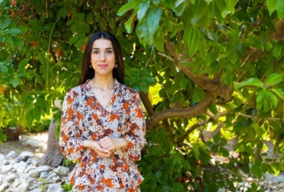 nadia murad standing in front of a tree. 